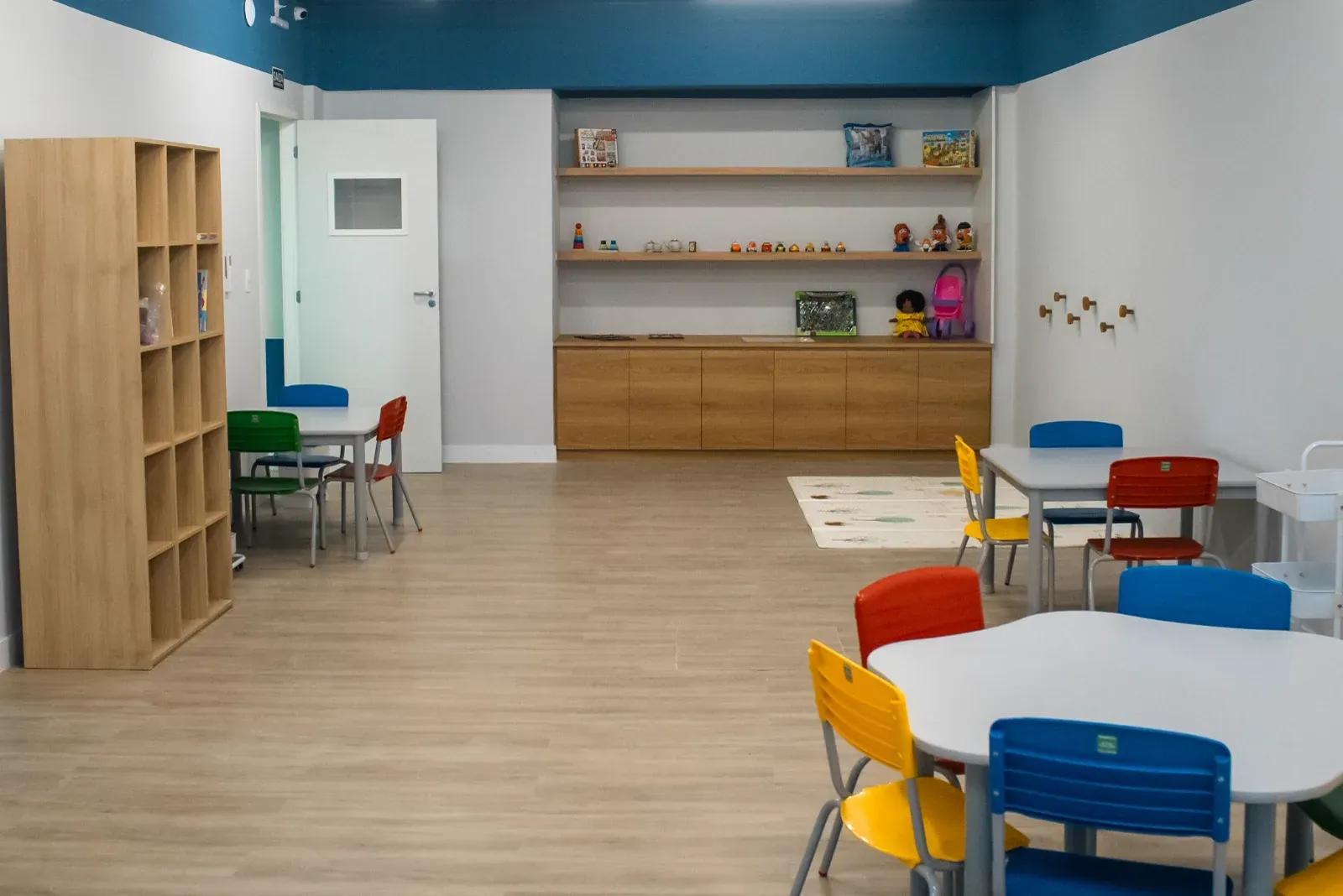 Sala de atendimento em grupo com mesas e cadeiras coloridas